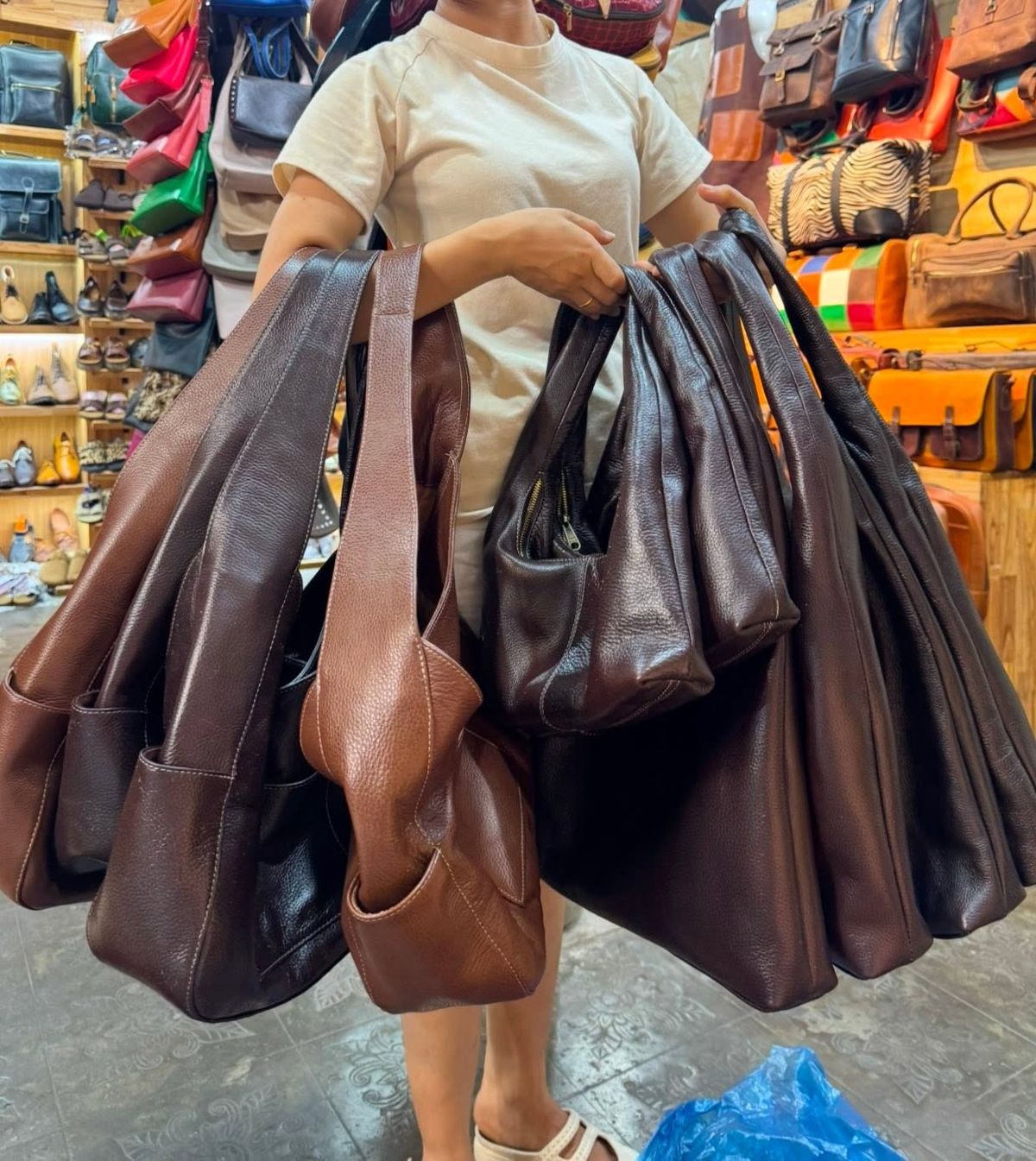 Customer holding a collection of brown leather hobo bags from Bison Leather Shop