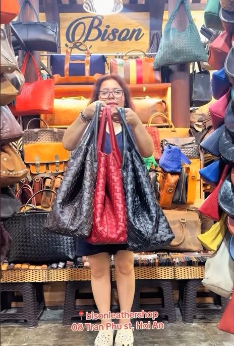 Customer holding oversized black and red woven leather tote bags at Bison Leather Shop